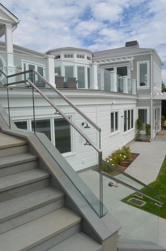 Overview showing two separate glass railings on the same project.   Base Shoe System on the stairs and posts with channel on the upper level.  This show a close up with the handrail brackets and through glass mounting.